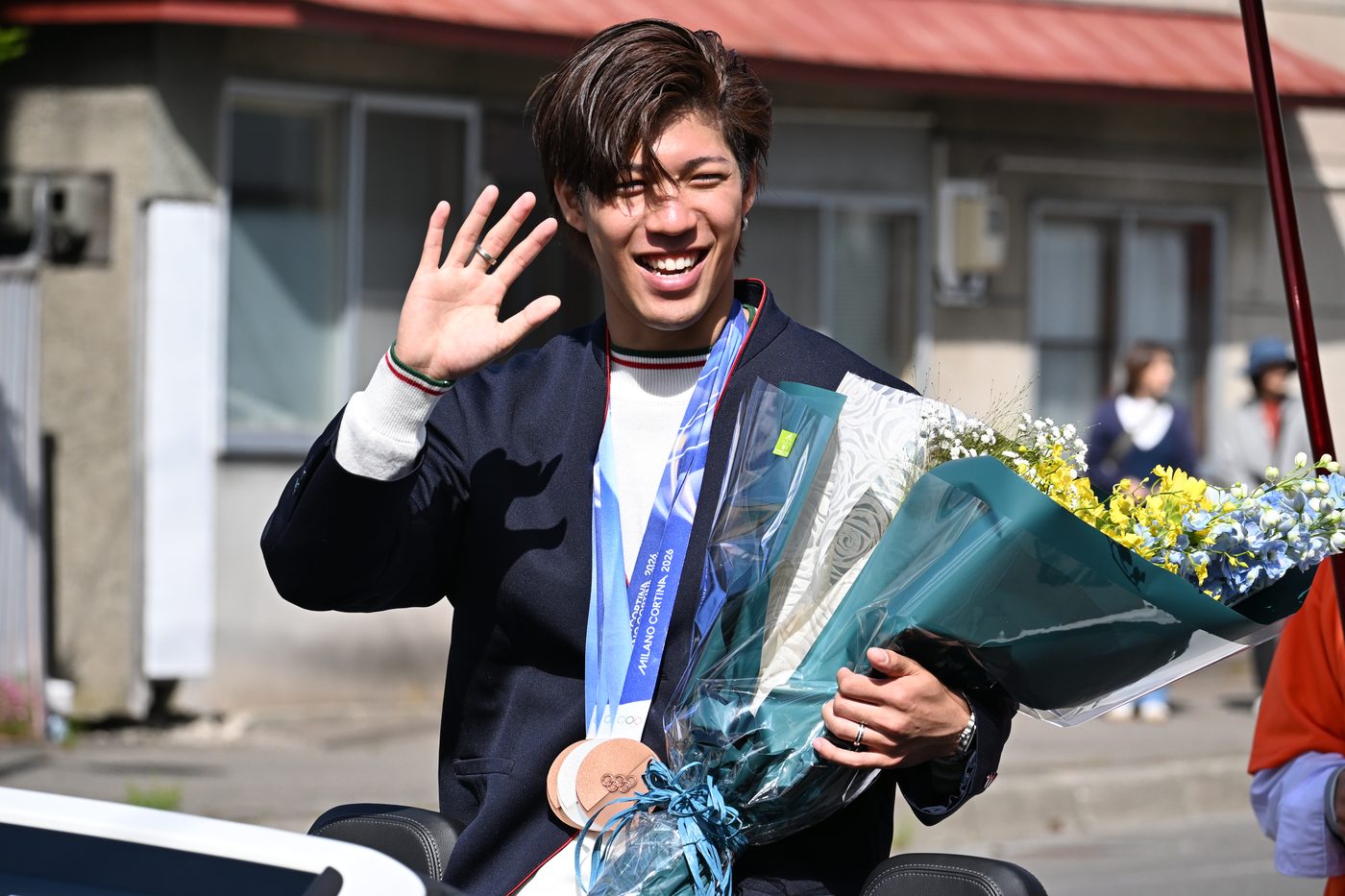 花束を手に、凱旋パレードで沿道の人々に応える二階堂蓮選手